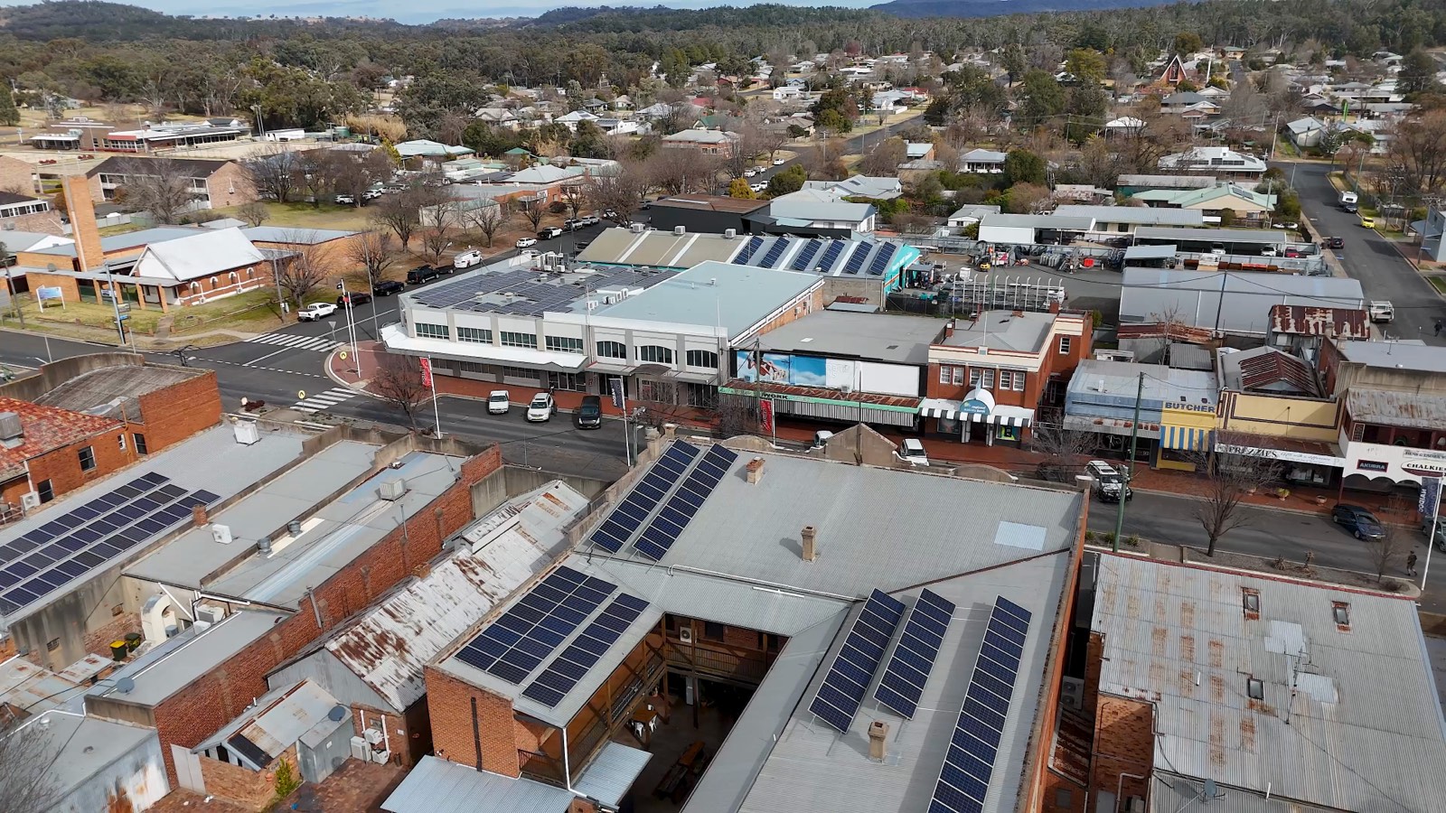 Aerial view of solar panels on several rooftops beside a town street